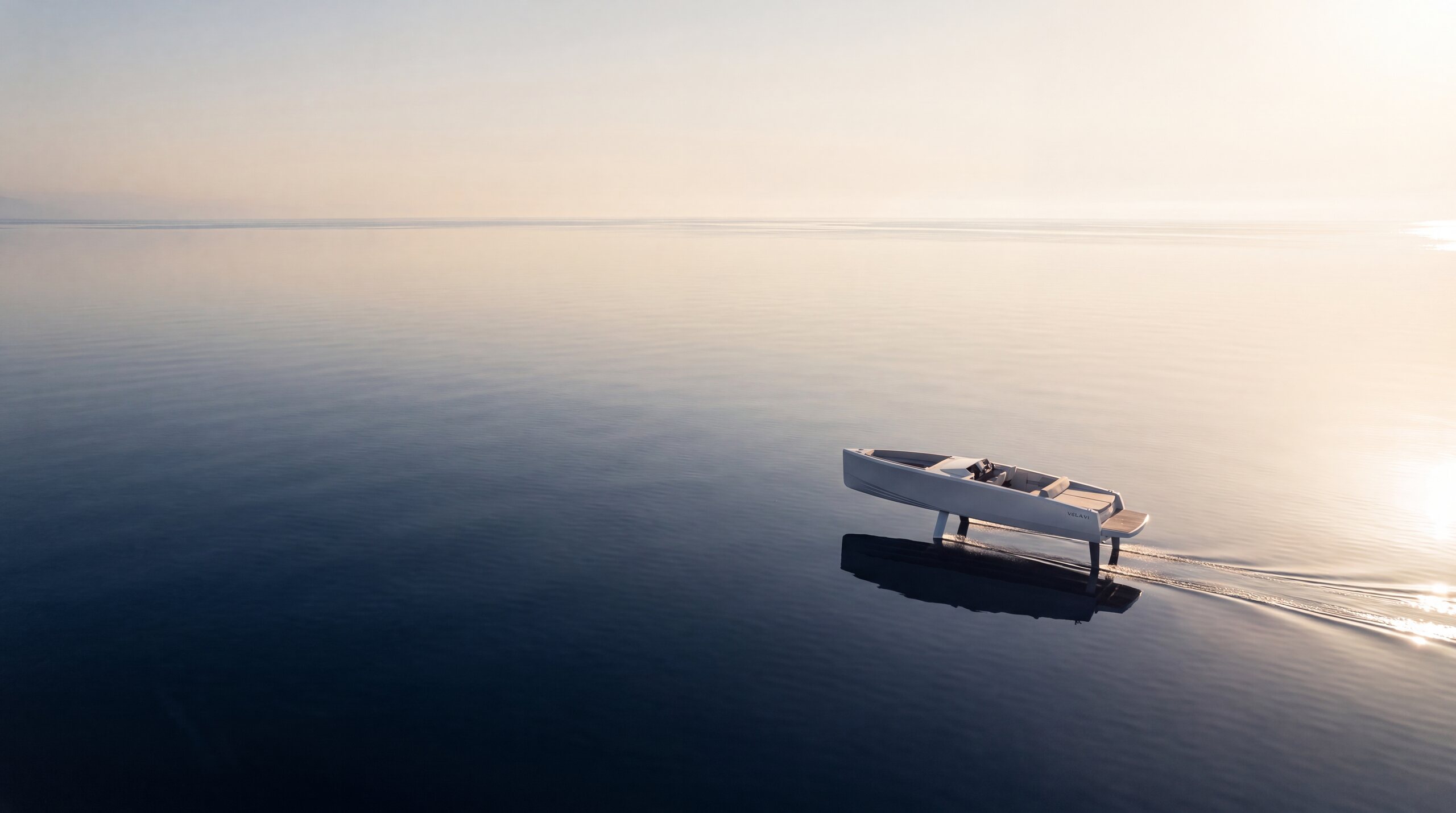 High aerial of VELA V1 flying across glassy open water